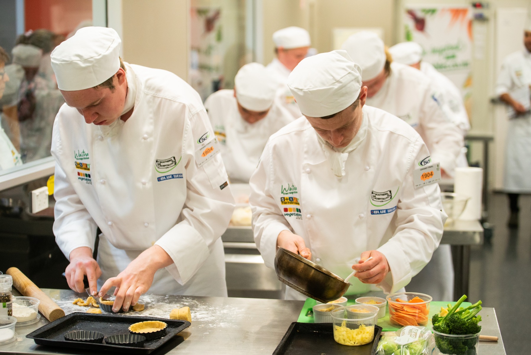 young male chefs cooking competition in whites 